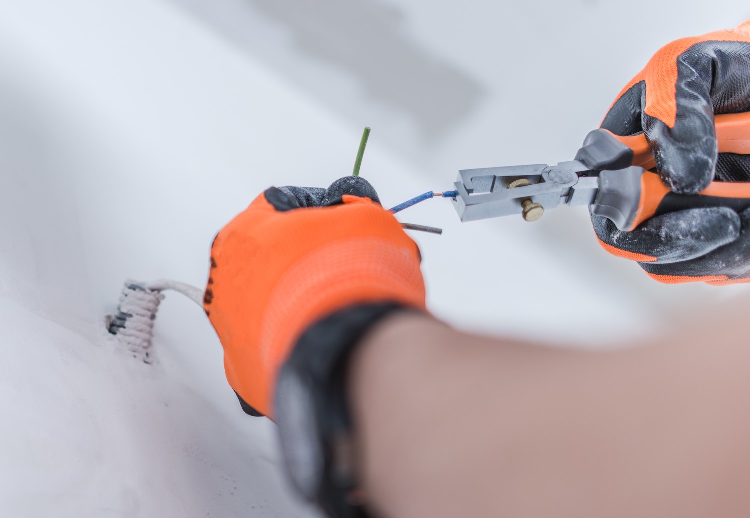 Closeup of hands with orange gloves installing electrical wires