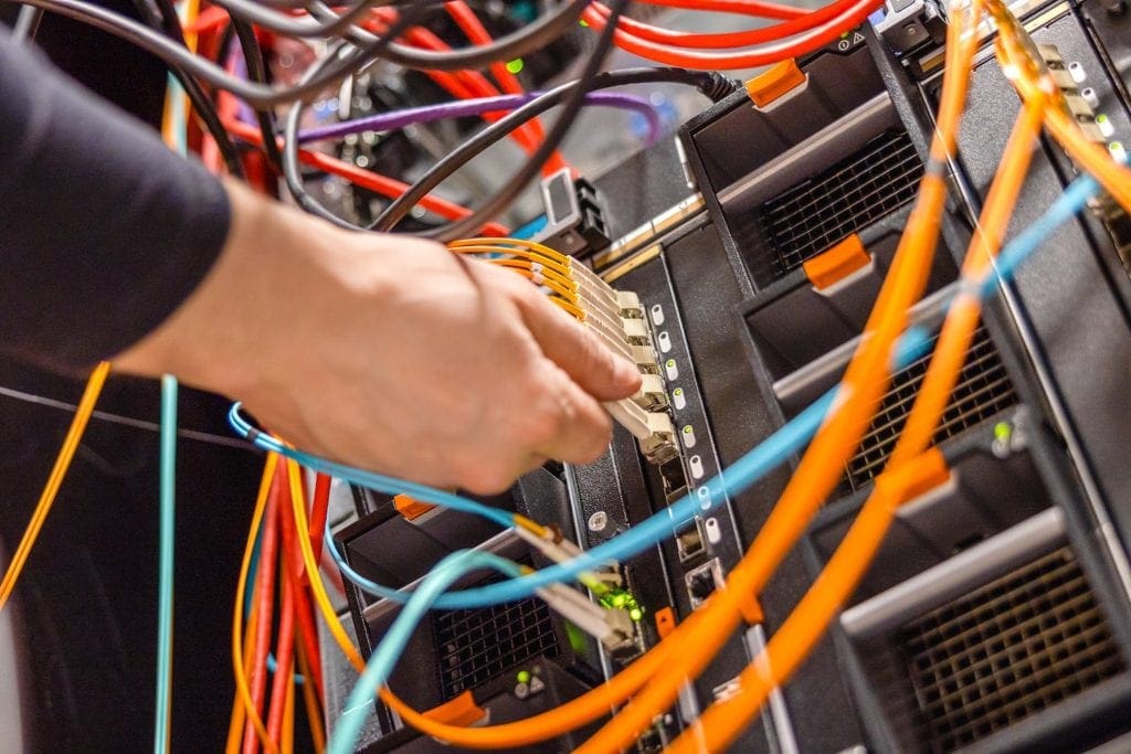 Male technician plugging fiber channel network cable into blade server switch