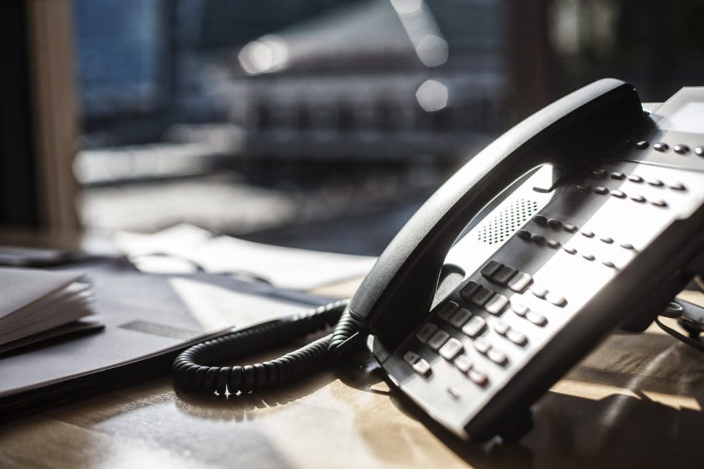 Closeup of telephone and desktop in an office.