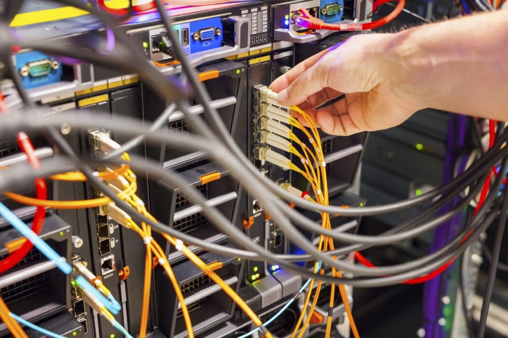 Hand plugging fiber cable into switch in data center
