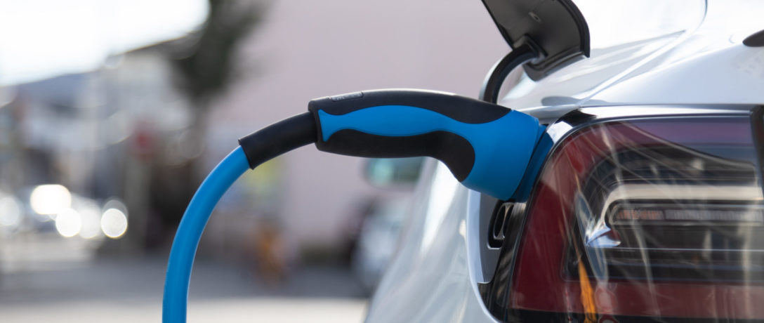 EV electric car pluged charging at a recharge station in the cit